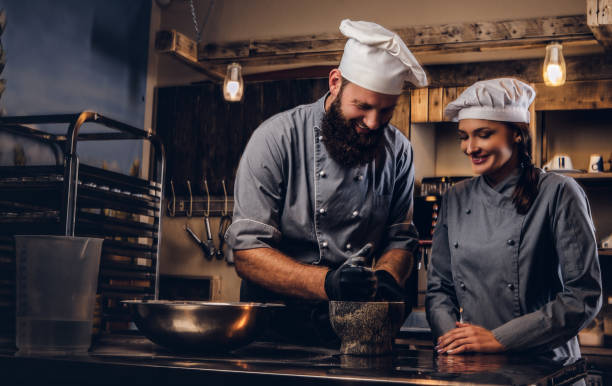 istock Chef grinds sesame seeds in a mortar for cooking bread. Chef teaching his assistant to bake the bread in bakery. 1076247570