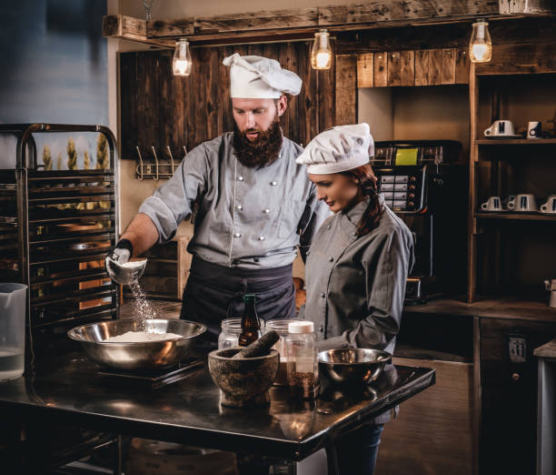 istock Chef pours the flour into a bowl. Chef teaching his assistant to bake the bread in the bakery. 1076247746