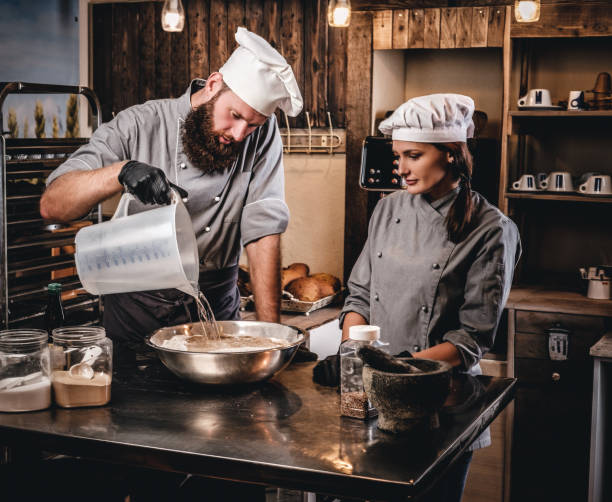 istock Chef mixes the ingredients for the dough. Chef teaching his assistant to bake bread in the bakery. 1076249434