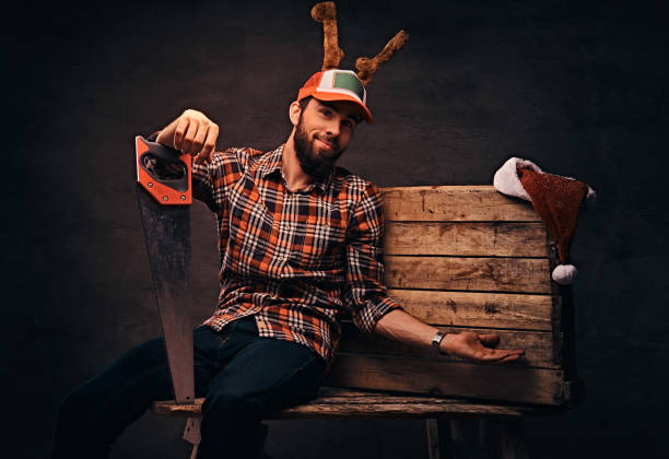 stolarz ubrany w zdobioną czapkę świąteczną siedzącą na drewnianej palecie. - santa claus christmas watch workshop zdjęcia i obrazy z banku zdjęć