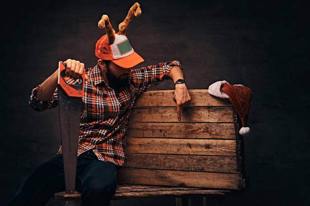 stolarz ubrany w zdobioną czapkę świąteczną siedzącą na drewnianej palecie. - santa claus christmas watch workshop zdjęcia i obrazy z banku zdjęć
