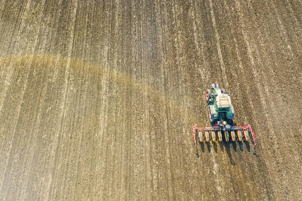 istock Farmer seeding crops at field. Seeding Aerial View. 1076266558