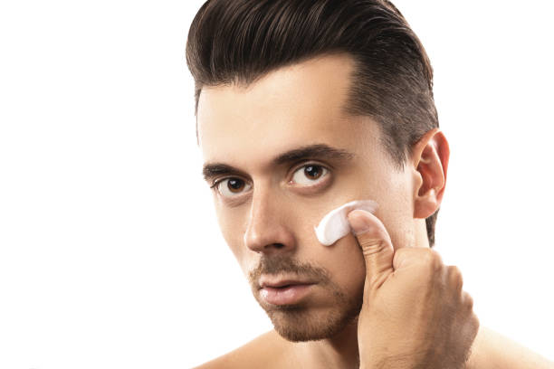 istock Young man is applying moisturizing cream on his face 1076273734