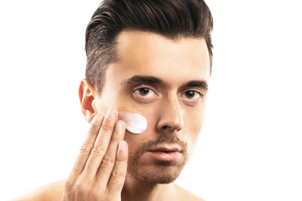 istock Young man is applying moisturizing cream on his face 1076273810