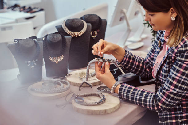 istock Elegantly dressed woman makes handmade necklaces, working with needles and thread in workshop. 1076283186