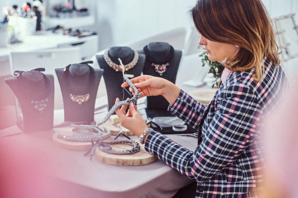 istock Elegantly dressed woman makes handmade necklaces, working with needles and thread in workshop. 1076283204