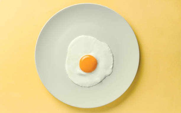 istock Fried egg tray on yellow background - Simple composition of egg on plate 1076297456