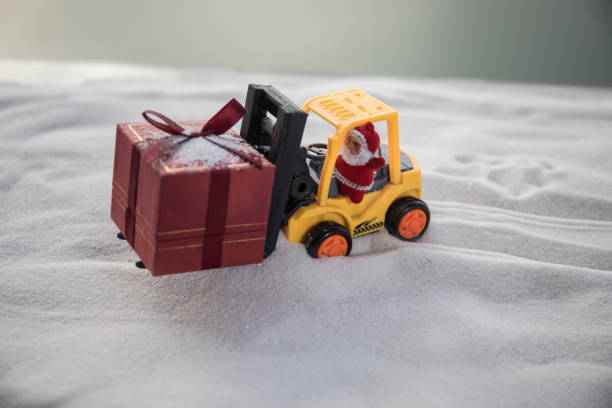 istock Miniature Gift Box by Forklift Machine on snow ,Determined Image for Christmas Holiday and Happy New Year Gift Celebration concept. 1076299874