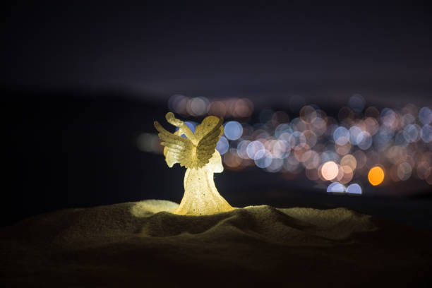 christmas angel on blur bokeh city lights at night on background. Little white guardian angel in snow. christmas angel on blur bokeh city lights at night on background. Little white guardian angel in snow. Christmas decoration pics of guardian angels stock pictures, royalty-free photos & images