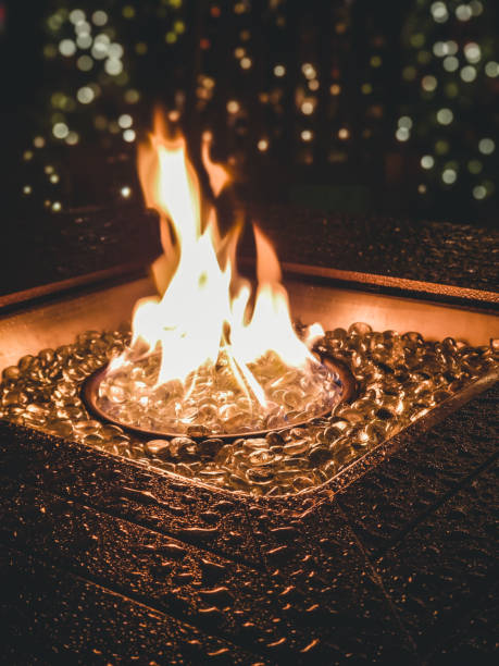 chimenea al aire libre mojado de la lluvia con llamas de oro. - blue flame natural gas fireplace fotografías e imágenes de stock
