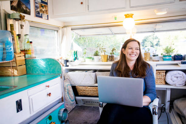 Young entrepreneur woman working from her RV A young woman setting up camp in the wilderness with her trailer tiny house photos stock pictures, royalty-free photos & images