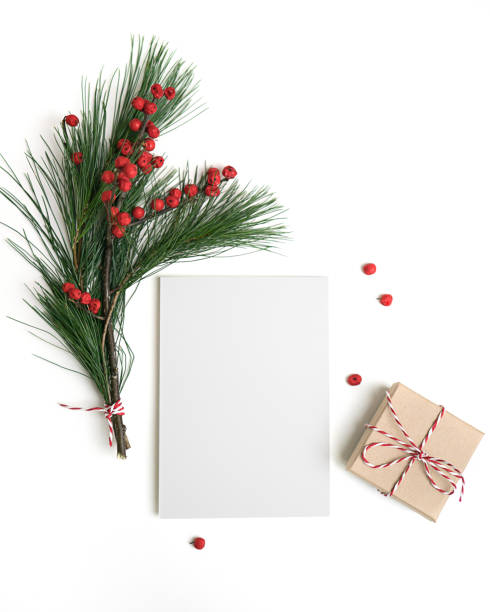 istock Christmas greeting card template. Empty paper mock up, gift box, fir tree branch with decorations, red berries, isolated on white background. 1076315460