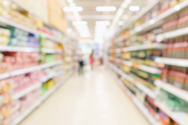 istock Supermarket aisle with customer blur defocused product shelves interior bokeh light background 1076327708
