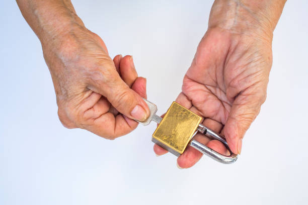 istock Senior woman's hand holding key unlock master key (Golden padlock ) isolated on white background 1076357538