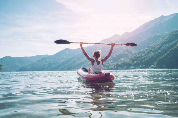 femme heureuse épris de canot sur le lac en été - mountain women victory winning photos et images de collection