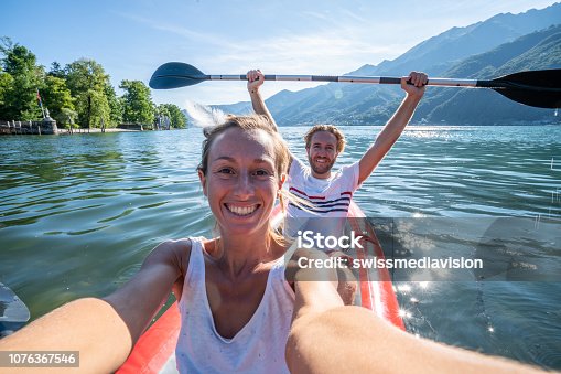 istock Young couple taking selfie portrait in red canoe on mountain lake 1076367546