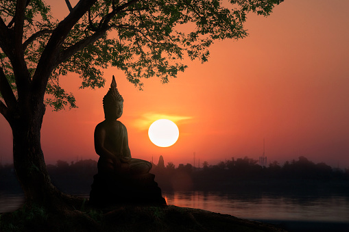 Water Reflection Silhouette of Buddha on sunset with mountain behind.end of Buddhist Lent