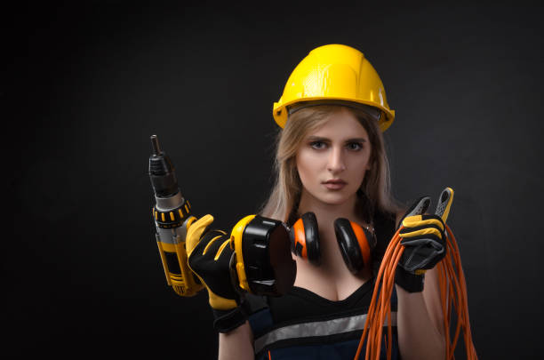 istock girl in construction clothes and protective equipment posing with a screwdriver 1076428246