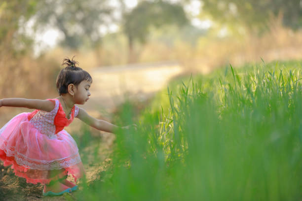 Portrait of happy girl, dancing. She wearing silk dress. Adolescent girl having fun, summertime in the countryside.  Sunlight  and atmospheric mood. Walking, happy, delight,