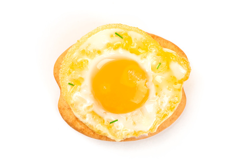 A photo of a quail egg, fried sunny side up, shot from above on a cracker on a white background with a place for text