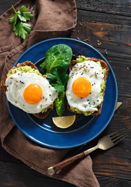 istock Healthy breakfast avocado toasts fried egg cheerful faces Top view healthy table 1076478572