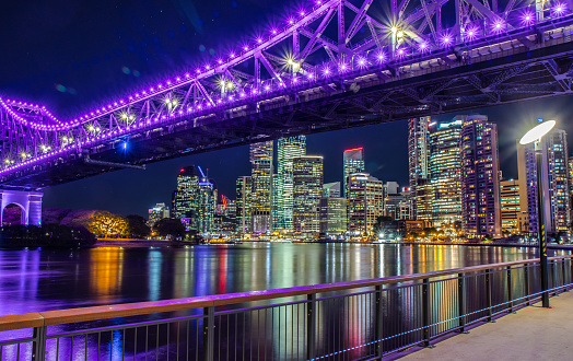 Cityscape of modern embankment under glowing bright bridge above city river on background of skyscrapers, Australia