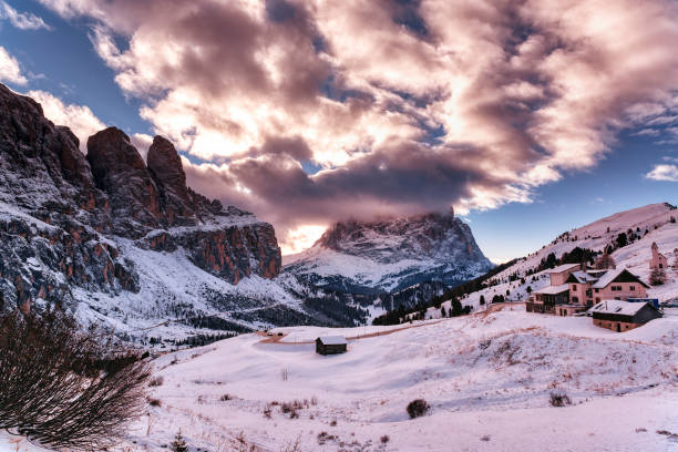 pink sunset over the Gardena Pass in winter Winter landscape from Gardena Pass in the Dolomites at the sunset with clouds over the top, Italian mountains - Trentino Alto-Adige, italy winter sunrise mountain snow stock pictures, royalty-free photos & images