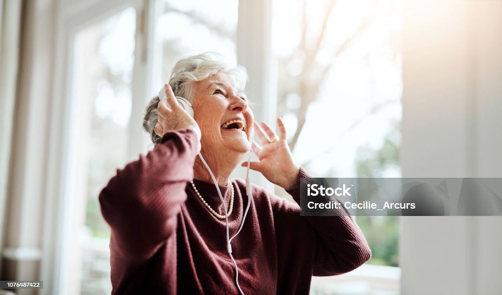 Turn up the volume of life Shot of happy senior woman listening to music with headphones at a retirement home Senior Adult Stock Photo