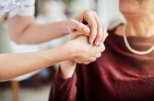 Cropped shot of a nurse holding an elderly woman’s hands in a retirement home