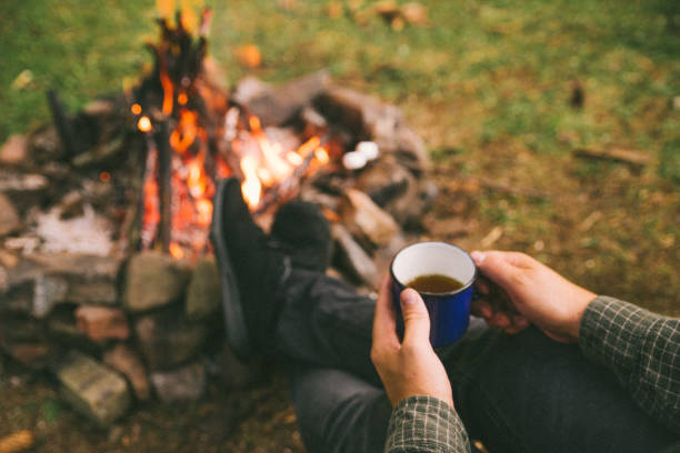 istock first point of view. man drinking tea in metal cup near camp fire 1076496846