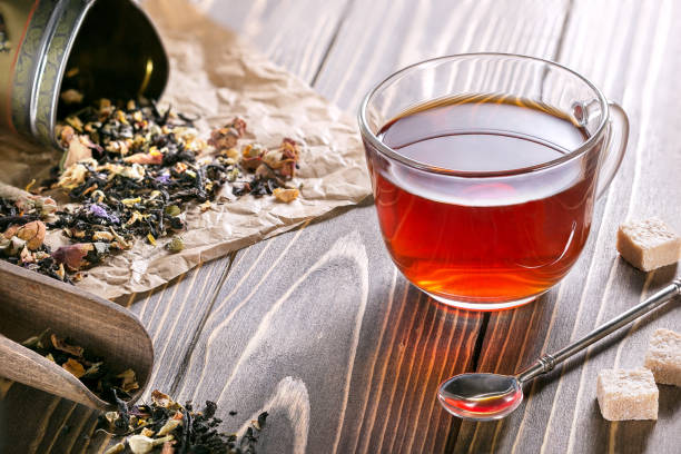istock Scattered flower tea leaves on paper and transparent cup with  herbal tea 1076502732