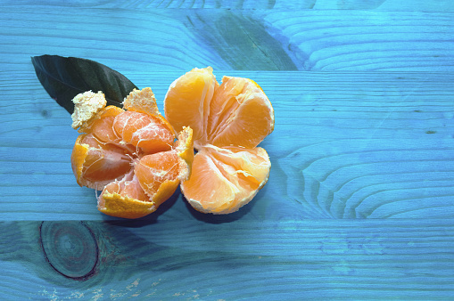 close up view of two opened mandarines on blue wooden background
