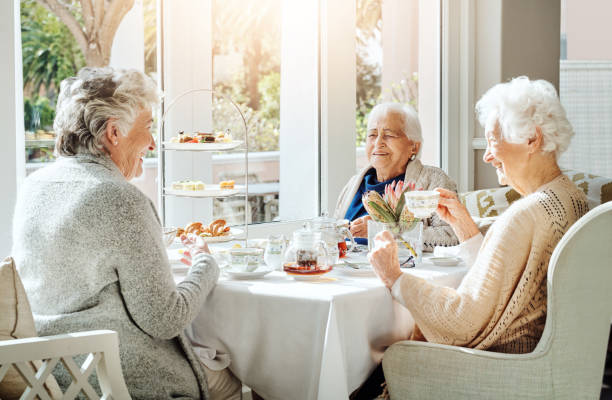 идеальное сочетание чая, торта и друзей - afternoon tea tea women table стоковые фото и изображения