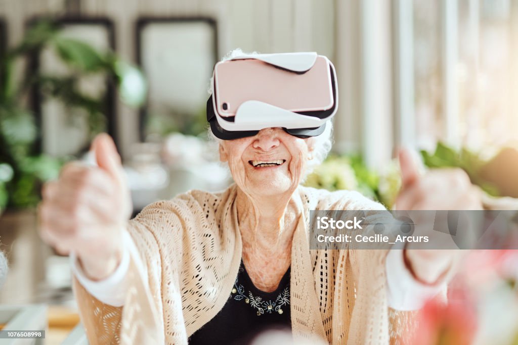 Bringing the outside world inside with virtual reality Shot of happy senior women using a virtual reality headset at a retirement home Senior Adult Stock Photo