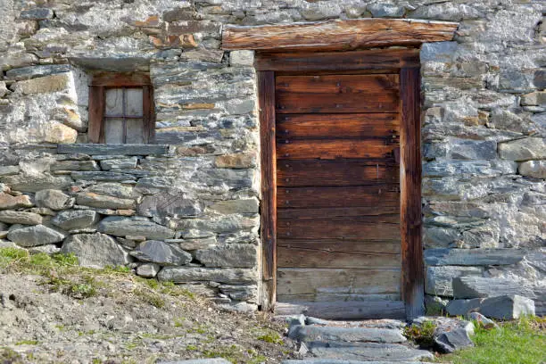 wooden door and little window of an old alpine chalet