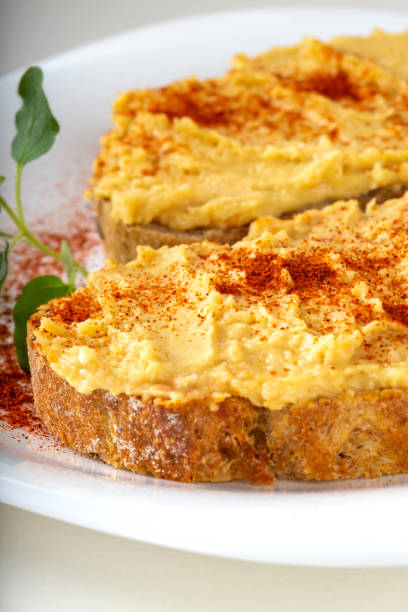 istock Two open sandwiches with hummus and paprika powder on a white plate 1076514864