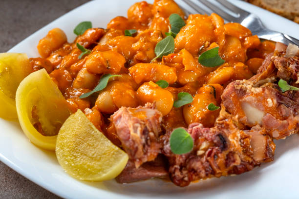 istock Beans stew with pork ribs and pickles on a white plate - close up view 1076514872