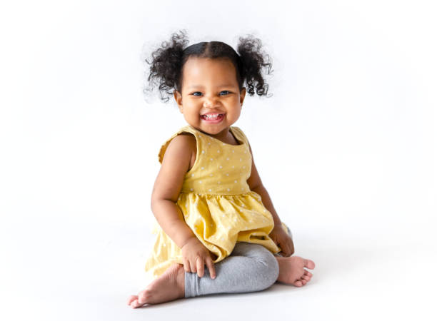 glückliches kleines mädchen in einem gelben kleid sitzen - kleidungsstück fotos stock-fotos und bilder