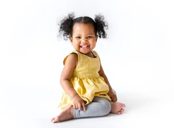 Photo of Happy little girl in a yellow dress sitting