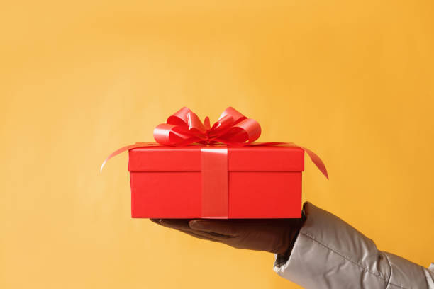 istock close-up partial view of man holding red gift box on yellow back 1076519552