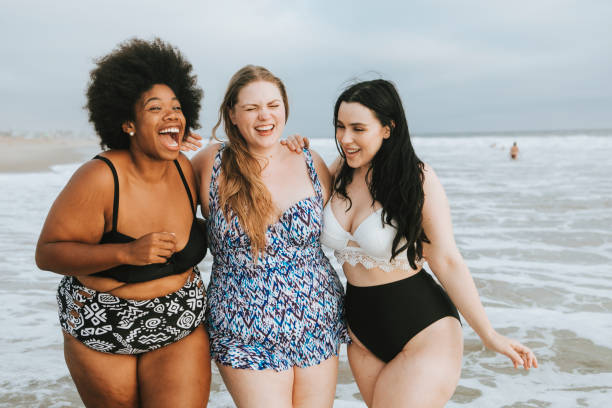 Cheerful plus size women enjoying the beach Cheerful plus size women enjoying the beach swimwear stock pictures, royalty-free photos & images