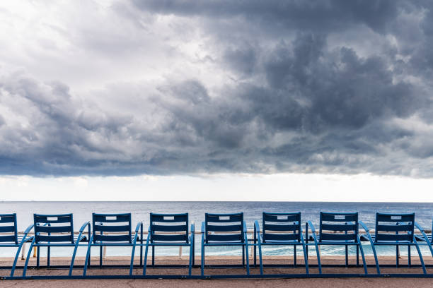 Sandy beach on the coast of the Baltic Sea in Strande / Kiel in Germany. With several beach chairs, a ferry and dark clouds after a rain shower.