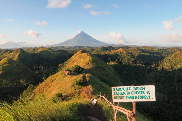 Natural Chocolate Hills A wide-view shot of the chocolate hills landscape, grassy hills can be seen as well as a mountain in the distance, followed by a clear blue sky. Hikers can be seen walking along the natural footpath. chocolate hills photos stock pictures, royalty-free photos & images