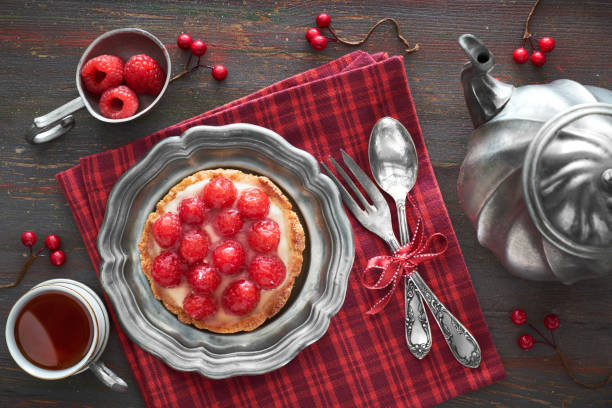 leckere himbeer-tarte auf einer vintaege metallplatte mit teekanne und tasse tee auf rot karierte serviette - raspberry table wood autumn stock-fotos und bilder