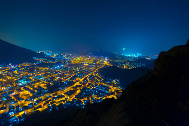 Panoramic skyline distance view on City of Mecca at night from Mountain Sur, where Prophet Muhammed and Abu Bakr used to hide from mushrikins in a cave stock photo