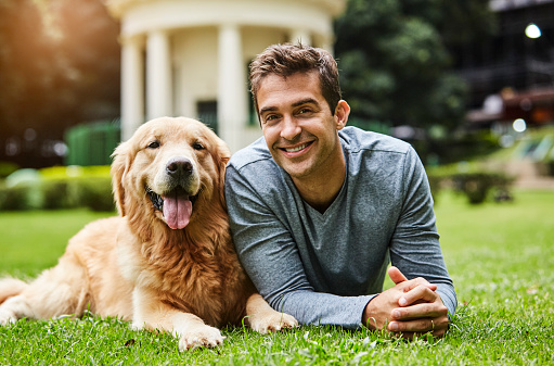 Handsome guy and dog lying on grass in park