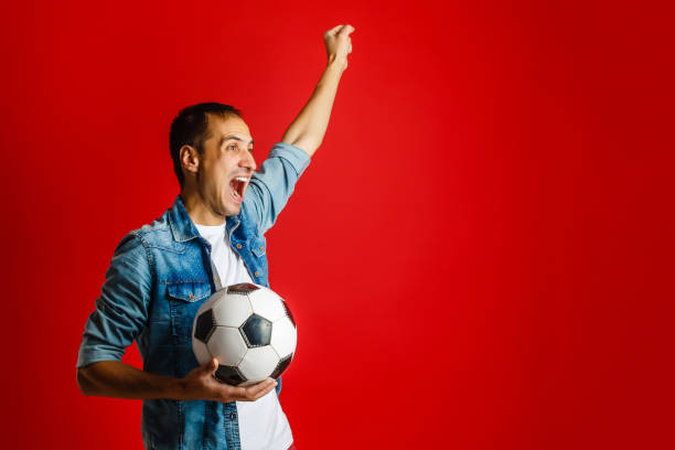 istock Man wearing red uniform celebrates on redbackground 1076573220