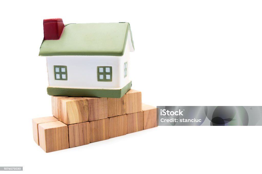 Miniature model house on fundation of wooden cubes, isolated on white Miniature model house on fundation of wooden cubes, isolated on white, real estate concept Architecture Stock Photo
