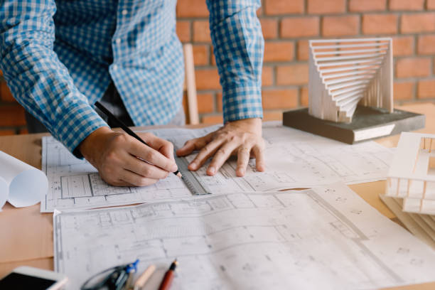 istock Engineering or architect reviewing blueprints and holding pencil on desk at home office. 1076575478