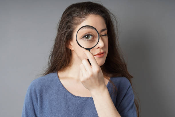 istock young woman looking through magnifying glass 1076583746